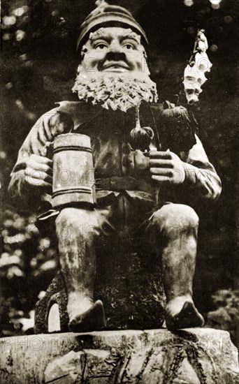 Elf in the sunken gardens. An model elf, flowers and tankard in hand, at Butchart gardens. Victoria, Canada, 21 June-4 July 1924. Victoria, British Columbia, Canada, North America, North America .