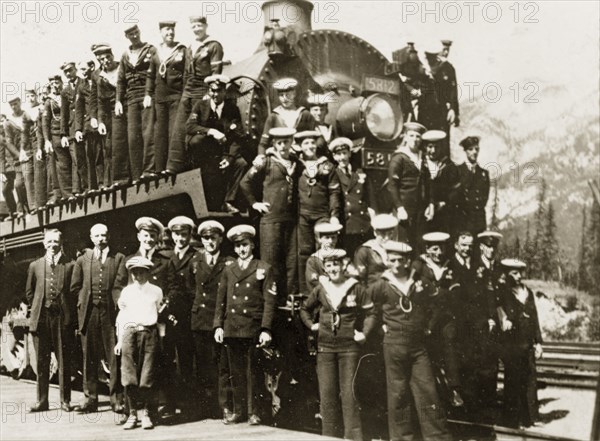 Trip to the Rockies. Uniformed sailors in the British Special Service Squadron pose for the camera around the engine of a train on a day trip to the Rocky mountains. Banff, Canada, 21 June-4 July 1924. Banff, Alberta, Canada, North America, North America .