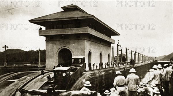 HMS Repulse is towed through a lock. One of eight electronic mules running on rails tows the HMS Repulse through a lock. Location unknown, circa 1924.