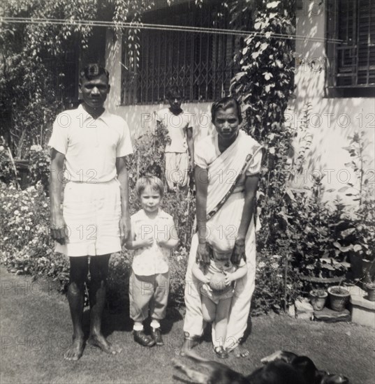 A colonial garden, India. An Indian servant and an ayah (nursemaid) entertain two young British children in the garden of a colonial house. Calcutta (Kolkata), India, circa 1954. Kolkata, West Bengal, India, Southern Asia, Asia.