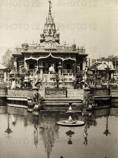 Temple on the water. Steps at an ornately decorated temple lead down into a fountain pool. India, circa 1954. India, Southern Asia, Asia.