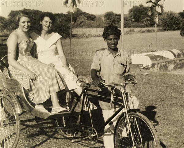 Eight annas just to sit there'. Audrey Leonard (left) and her Australian friend Topsy, pose for the camera aboard a bicycle-rickshaw. Audrey comments disapprovingly on the reverse of the photograph that it cost the pair 'eight annas just to sit there'. India, circa 1954. India, Southern Asia, Asia.