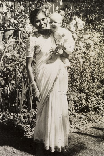 An Indian ayah poses with infant. Dressed in a flowing sari, an Indian ayah (nursemaid) identified as 'Asha' holds up a smiling British baby for the camera. Calcutta (Kolkata), India, circa 1954. Kolkata, West Bengal, India, Southern Asia, Asia.