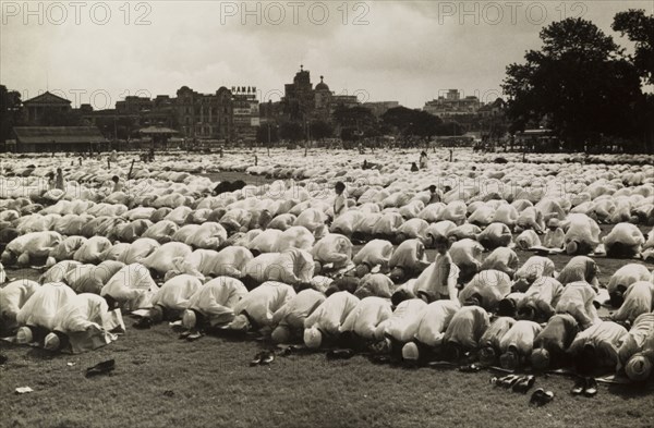 Kneeling in prayer for Eid. Hundreds of Muslim men, their shoes removed, kneel on prayer mats as they bow their heads in prayer during the Islamic festival of Eid. Calcutta (Kolkata), India, circa 1954. Kolkata, West Bengal, India, Southern Asia, Asia.