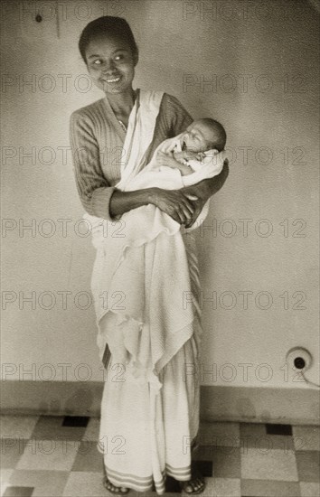 An Indian ayah with infant. Dressed in a flowing sari, an smiling Indian ayah (nursemaid) holds a yawning baby in her arms. Calcutta (Kolkata), India, circa 1954. Kolkata, West Bengal, India, Southern Asia, Asia.