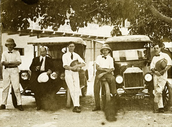 Tamlin and colleagues. Mr Alfred Tamlin (right) poses with four colleagues beside two motor vehicles. Probably Accra, Gold Coast (Ghana), 4 April 1917. Ghana, Western Africa, Africa.