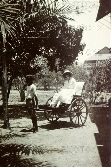 Mrs Tamlin in a taxi. Mrs Dorothy Tamlin takes a ride in a rickshaw taxi. Probably Ghana, circa 1918., Western Africa, Africa.