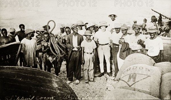 Tamlin and cocoa. Mr Alfred Tamlin (the European man in the centre) stands amongst a crowd of African labourers, regarding loaded sacks of cocoa on the banks of a river. Western Africa, circa 1918., Western Africa, Africa.