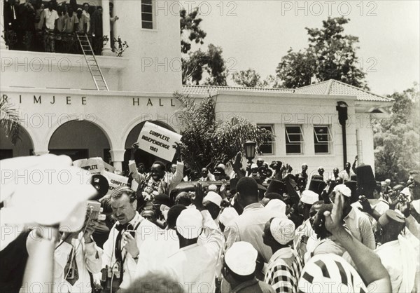 Complete independence, Tanzania 1961. Official publicity shot for the Tanganyikan government. Dr Julius Kambarage Nyerere is greeted by crowds outside a government building as Tanganyika achieves independence. Carried on the shoulders of his supporters, he proudly holds up a placard that reads 'Complete Independence 1961'. Tanganyika (Tanzania), 1961. Tanzania, Eastern Africa, Africa.