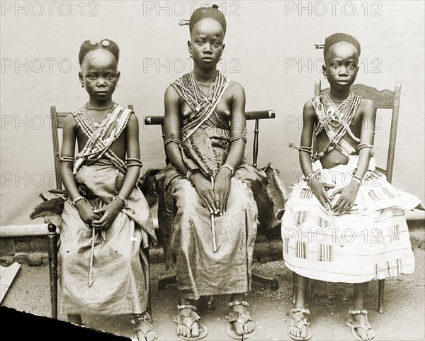 Three Fante girls, Gold Coast. Outdoors portrait of three adolescent girls wearing wrap skirts and beaded necklaces. Saltpond, Gold Coast (Ghana), 1917. Saltpond, West (Ghana), Ghana, Western Africa, Africa.