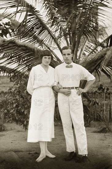 Alfred and Dorothy Tamlin. Amateur portrait of Alfred Tamlin and his wife Dorothy, nee Lamble, standing in front of a palm tree. Half Assini, Gold Coast (Ghana), May 1920. Ghana, Western Africa, Africa.