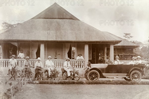 Miller Brothers' bungalow. European staff of Miller Brothers agency pose on motorbikes and in a car outside a large bungalow with wide verandas. Probably Accra, Gold Coast (Ghana), circa 1918. Ghana, Western Africa, Africa.