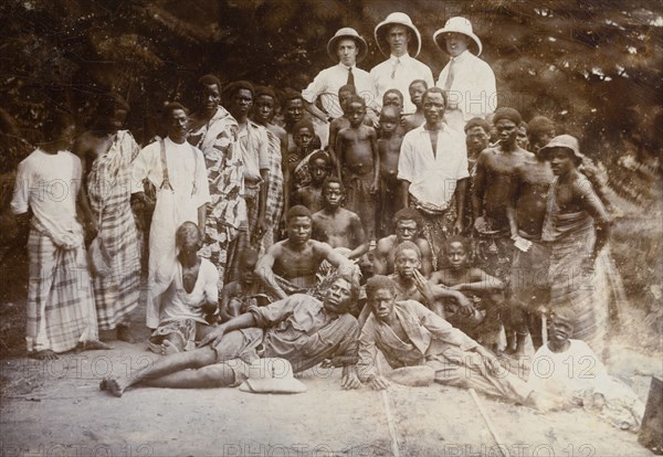 Group photograph, Western Africa. Mr Alfred Tamlin (the European on the left) poses for the camera with two European colleagues and a large group of African men and boys. Western Africa, circa 1920., Western Africa, Africa.