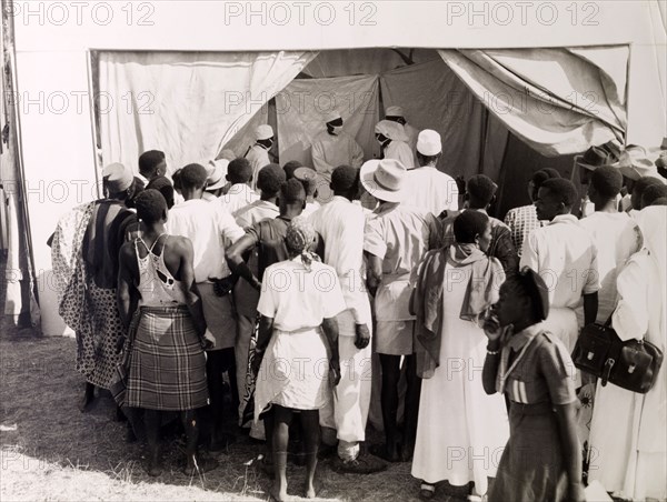 Public health demonstration. Official publicity shot for the Tanganyikan government. A crowd of people watch a public demonstration from health professionals. Tanganyika Territory (Tanzania), circa 1950. Tanzania, Eastern Africa, Africa.