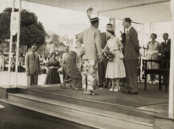 Queen Elizabeth meets a Nigerian chief. Queen Elizabeth II greets a Nigerian chief and his wife during a royal tour of Nigeria (28 January-16 February 1956). Her husband, Prince Philip, Duke of Edinburgh, stands at her side on the right. Nigeria, circa January 1956. Nigeria, Western Africa, Africa.
