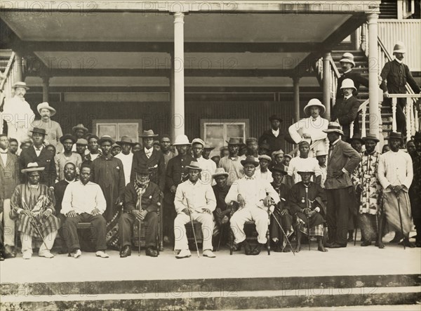 Edward VII's Coronation Day, Nigeria. A number of notable European and Nigerian men pose for a group portrait outside Government House to celebrate the coronation of King Edward VII. Bonny, Nigeria, circa 9 August 1902. Bonny, Rivers, Nigeria, Western Africa, Africa.