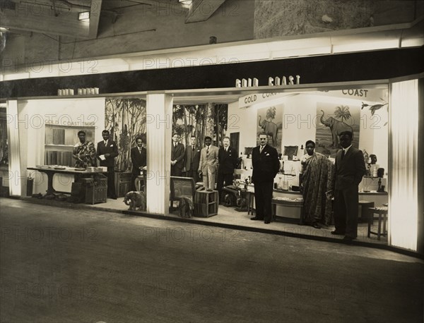 Gold Coast stand at British Industries Fair. An official photograph, taken for the Gold Coast Colonial Office, of the Gold Coast stand at the British Industries Fair. British and African men attend the stall, which displays a collection of African objects and an exhibit about Gold Coast timber. London, United Kingdom, 1950. London, London, City of, England (United Kingdom), Western Europe, Europe .
