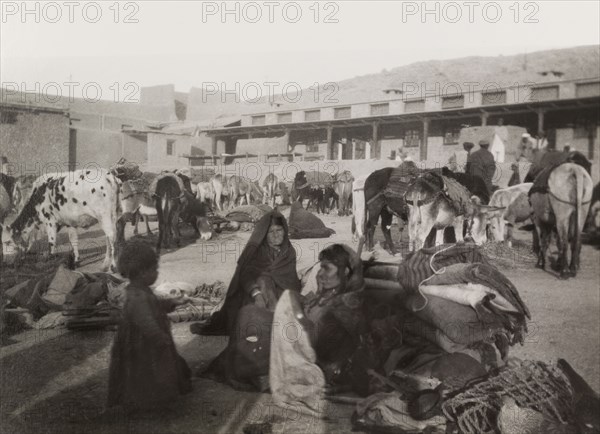 Bedouins take a rest. A group of bedouins take a rest from travelling to feed their animals in an enclosed courtyard. Amongst their belongings, heaped on the ground, are cooking pots and blankets. Probably Northern Africa, circa 1925., Northern Africa, Africa.