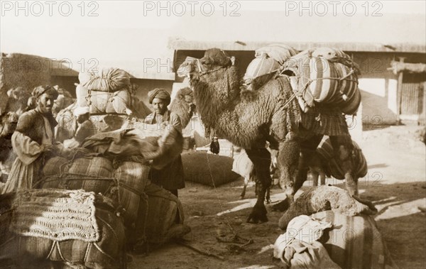 Bedouins unload their belongings. A group of bedouins unload bundles of belongings from their camels in an enclosed courtyard. Probably Northern Africa, circa 1925., Northern Africa, Africa.