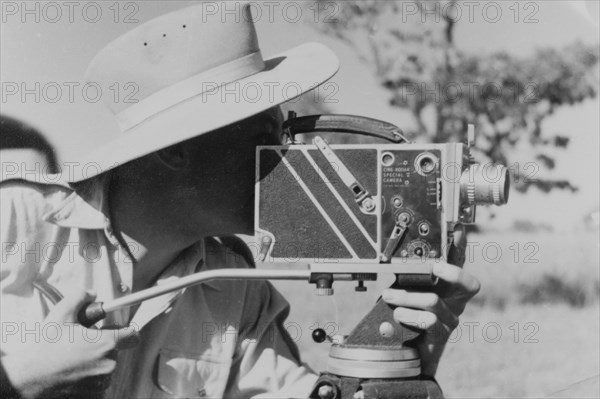 Filming for the Central African Film Unit. A European cameraman operates a movie camera on location at Goromonzi, during the shooting of a police film for the Central African Film Unit (CAFU). Goromonzi, Southern Rhodesia (Zimbabwe), May 1954. Goromonzi, Mashonaland East, Zimbabwe, Southern Africa, Africa.