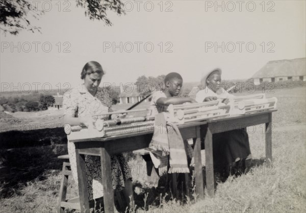 Chalimbana Training College. A European and two African women weave outdoors using hand looms at Chalimbana (teacher) Training College. Lusaka, Northern Rhodesia (Zambia), circa 1952., Lusaka, Zambia, Southern Africa, Africa.