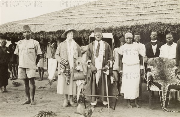 Lady Bledisloe with an African chief. Lady Bledisloe poses beside an African chief and his wife outside a low, thatched roof building. Her husband, Lord Bledisloe, was Head of the Bledisloe Commission, established in 1935. Southern Africa, 1937., Southern Africa, Africa.