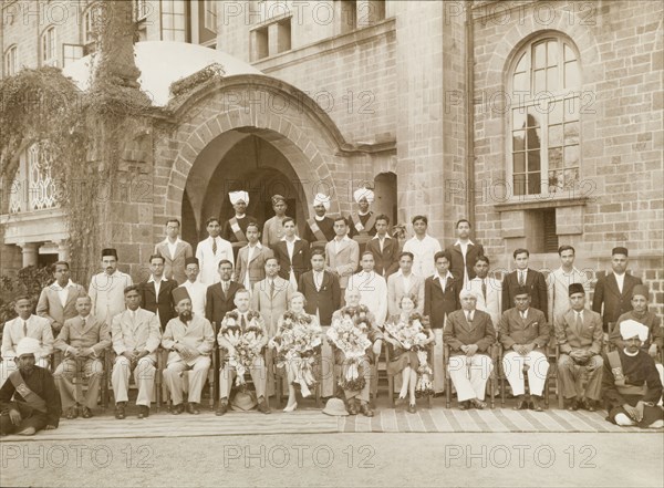 Government employees, India. Two British couples, adorned with garlands and bouquets of flowers, pose at the centre of a group portrait, surrounded by rows of Indian government workers. The British man to the left may be Mr Caffin, a one time District Officer of the Northern Province. India, circa 1945. India, Southern Asia, Asia.
