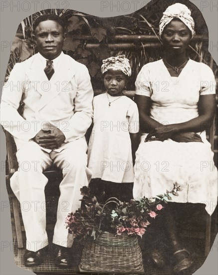 Portrait of a Nigerian family. Portrait of a Nigerian family, dressed in typical Western-style clothing except for the patterned headscarves worn by the woman and child. Southern Nigeria, circa 1948. Nigeria, Western Africa, Africa.