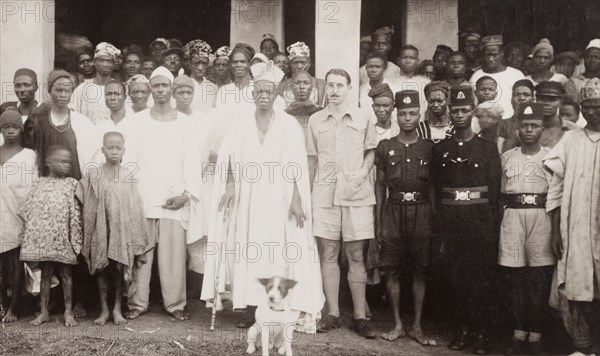 Cyril Iles with a Nigerian chief. British colonial officer, Cyril Iles, poses for the camera beside a Nigerian chief. The pair are surrounded by several uniformed police officers and a crowd of civilians. Probably Ikare, Nigeria, circa 1950. Ikare, Ondo, Nigeria, Western Africa, Africa.