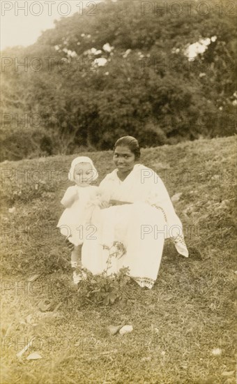 Ayah with toddler. Outdoors portrait of a young British toddler, posing for the camera with her Indian ayah (nursemaid). Bombay (Mumbai), India, 1922. Mumbai, Maharashtra, India, Southern Asia, Asia.