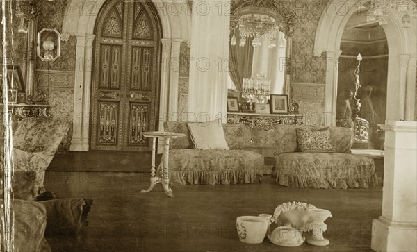 Interior at the Palace of Mysore. An opulent interior inside the Palace of Mysore. Decorated with ornate wallpaper and mirrors, the room is furnished with comfortable couches and elaborate chandeliers. Mysore, Karnataka, India, 1922. Interior of Palace at Mysore, the official residence of the former royal family. It is now one of the most famous tourist attractions in Mysore. Mysore, India, 1922. Mysore, Karnataka, India, Southern Asia, Asia.