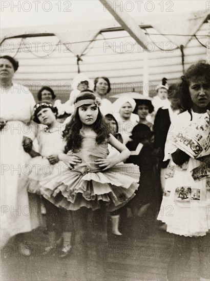 Fancy dress party aboard RMS Arundel Castle. A young girl, dressed in a ballet outfit with tutu, stands with her hands on her hips, looking rather displeased during a children's fancy dress party aboard RMS Arundel Castle, enroute from southern Africa to England. Location unknown, circa 1930.