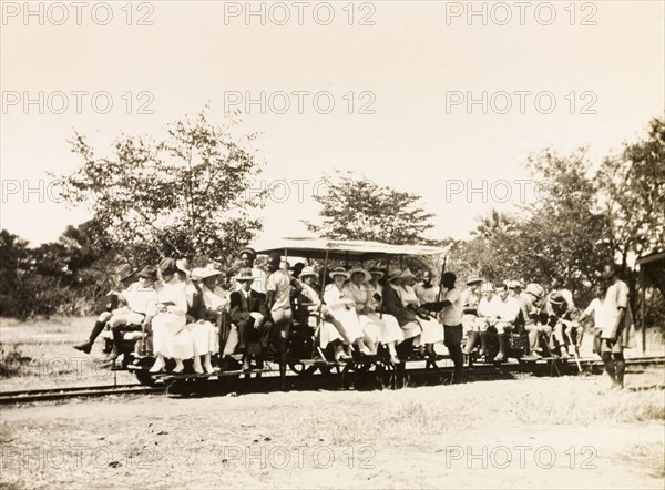 Transportation to Livingstone. After arriving at a nearby landing stage, a large party of Europeans climb into an open rail car, ready to make their journey to Livingstone. A number of African servants prepare to push the car for three miles uphill to its destination. Northern Rhodesia (Zambia), circa 1930., South (Zambia), Zambia, Southern Africa, Africa.