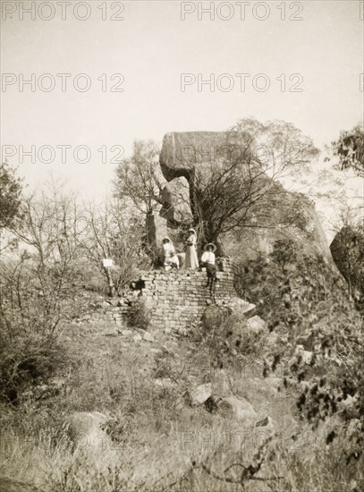 Exploring the Khami ruins. Four European women, wearing sun hats and summer dresses, explore the remains of a stone wall at the ancient, ruined city of Khami. Khami, Southern Rhodesia (Zimbabwe), circa 1930., Matabeleland North, Zimbabwe, Southern Africa, Africa.