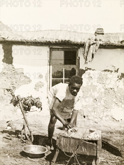 A domestic servant at Balloch Farm. A domestic servant at Balloch Farm scrubs his hands clean, using a bar of soap, a bowl and a crudely constructed wooden washstand. Near Gwelo, Southern Rhodesia (near Gweru, Zimbabwe), circa 1930. Gweru, Midlands, Zimbabwe, Southern Africa, Africa.