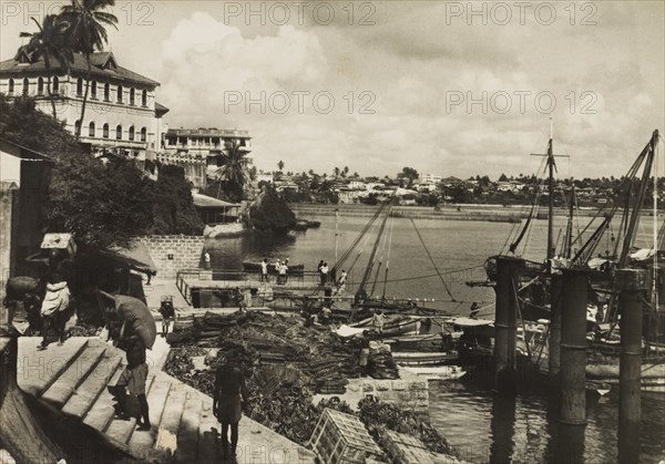 Mombasa Old Port, 1950. View across Mombasa's Old Port showing tradesmen unloading crates from small vessels docked nearby. Mombasa, Kenya, 1950. Mombasa, Coast, Kenya, Eastern Africa, Africa.