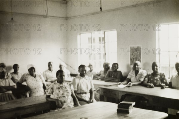 The wives of trainee priests attend college. The wives of trainee priests sit at their desks in a classroom at St. Paul's United Theological College in Limuru. The college was established by missionaries to train African ordinands for the priesthood and to educate their wives. Limuru, Kenya, circa 1956. Limuru, Central (Kenya), Kenya, Eastern Africa, Africa.