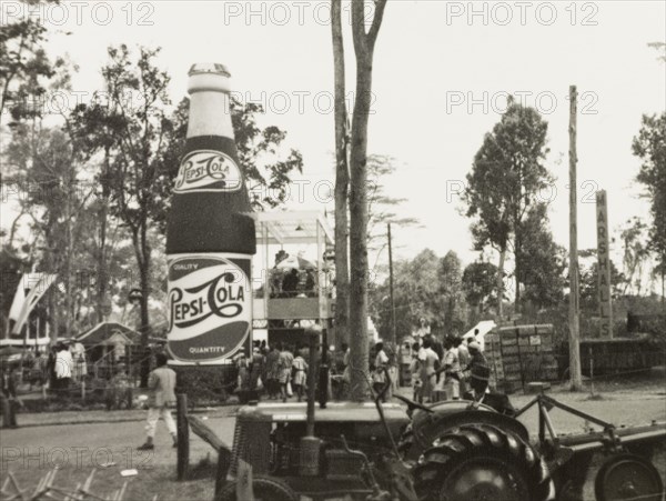 Pepsi Cola' at the Royal Show. A giant 'Pepsi Cola' bottle advertises the drink to passsers-by at the Royal Show. Nairobi, Kenya, circa 1956. Nairobi, Nairobi Area, Kenya, Eastern Africa, Africa.