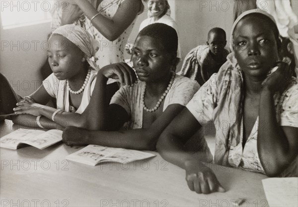 African women attend a missionary college. African women attend classes at a Methodist missionary college in Mombasa, sitting at a shared desk with their illustrated books open in front of them. Mombasa, Kenya, circa 1957. Mombasa, Coast, Kenya, Eastern Africa, Africa.