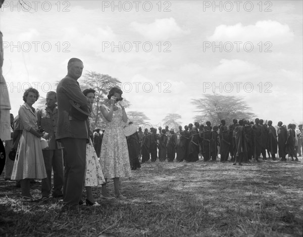 Princess Margaret watches a Maasai dance. Princess Margaret and her entourage watch from the sidelines as Maasai dancers wearing traditional dress prepare for a performance. Amboseli, Tanganyika Territory (Tanzania), 23 October 1956. Amboseli, Kilimanjaro, Tanzania, Eastern Africa, Africa.