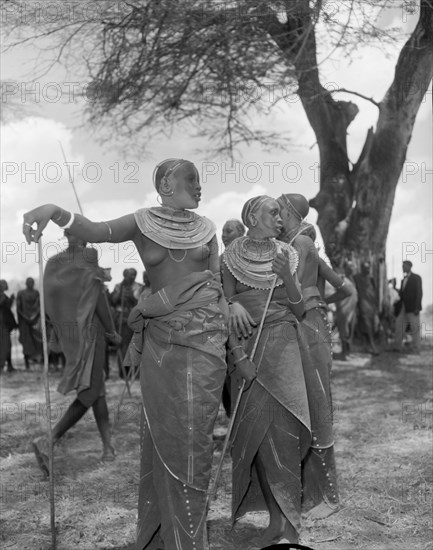 Female Maasai dancers. Two young Maasai women wearing traditional dress and ornate jewellery pause for thought at the welcoming ceremony provided for Princess Margaret. Amboseli, Tanganyika Territory (Tanzania), 23 October 1956. Amboseli, Kilimanjaro, Tanzania, Eastern Africa, Africa.