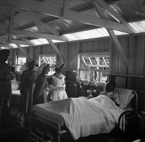 Princess Margaret at a British Military Hospital. Princess Margaret visits the bedside of a young male patient at the British Military Hospital's African ward. She is accompanied by two nurses and a man in military uniform. Nairobi, Kenya, 21 October 1956. Nairobi, Nairobi Area, Kenya, Eastern Africa, Africa.