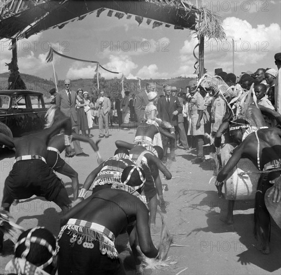 Welcoming dance for Princess Margaret. Princess Margaret is introduced to individuals in the crowd as a group of Wakamba dancers in traditional dress perform an energetic dance with drums to welcome her. Machakos, Kenya, 22 October 1956. Machakos, East (Kenya), Kenya, Eastern Africa, Africa.