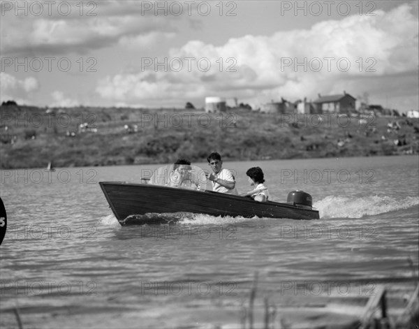 Joyriders at the Aquasports Regatta. Three youngsters take a ride in a speedboat across a lake at the Aquasports Regatta. Kenya, 28 October 1956. Kenya, Eastern Africa, Africa.