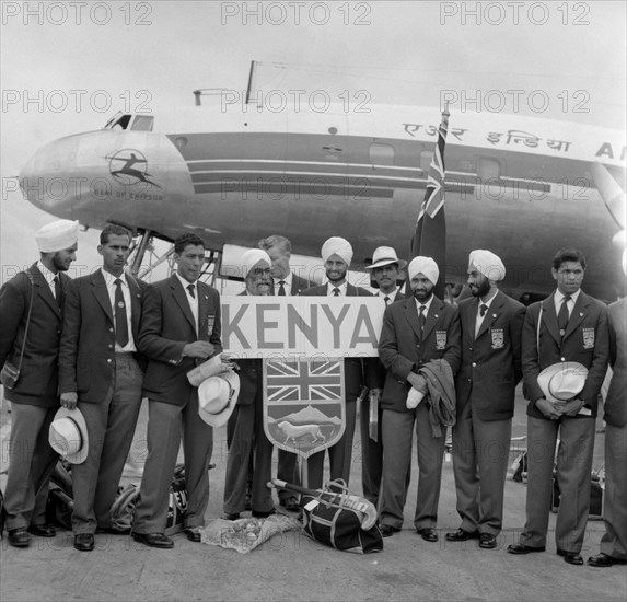 The 1956 Kenyan Olympic hockey team. The 1956 Kenyan Olympic hockey team pose with the Kenyan shield in front an aeroplane that is due to take them to India. Kenya, 31 October 1956. Kenya, Eastern Africa, Africa.
