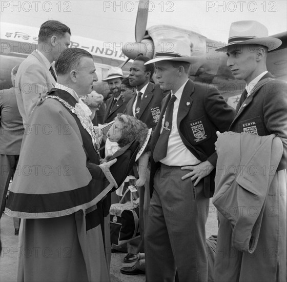 The Kenyan Olympic team depart. A local Mayor bids farewell to the 1956 Kenyan Olympic team as they prepare to depart on a plane. The team's blazers are embroidered with the British/Kenyan flags and the Kenyan mascot, a lion, can be seen under a team member's arm. Kenya, 31 October 1956. Kenya, Eastern Africa, Africa.