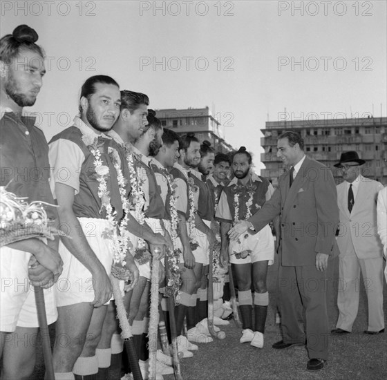 The 1956 Kenyan Olympic hockey team. A suited official shakes hands with a line up of players from the 1956 Kenyan Olympic hockey team. The team have just won a match against an opposing team from Goa and wear floral garlands around their necks. Bombay (Mumbai), India, 2 November 1956. Mumbai, Maharashtra, India, Southern Asia, Asia.