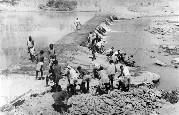 Mau Mau detainees build a dam. Prisoners build a dam as part of the government's 'rehabilitation' programme for Mau Mau detainees. Kenya, circa 1954. Kenya, Eastern Africa, Africa.