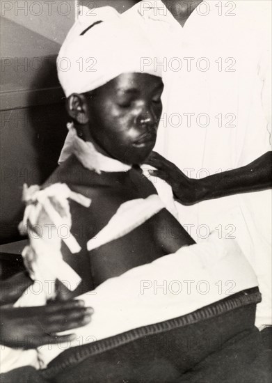 Surviving victim of the Lari massacre. A bandaged Kikuyu woman, one of the few survivors of the Lari massacre carried out by Mau Mau fighters, recovers in hospital. Kenya, March 1953. Kenya, Eastern Africa, Africa.