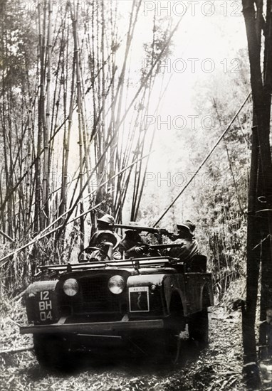 King's African Rifles patrol. A military jeep, driven by armed men from the King's African Rifles, patrols a bamboo forest during the war against Mau Mau rebels. Kenya, circa 1953. Kenya, Eastern Africa, Africa.